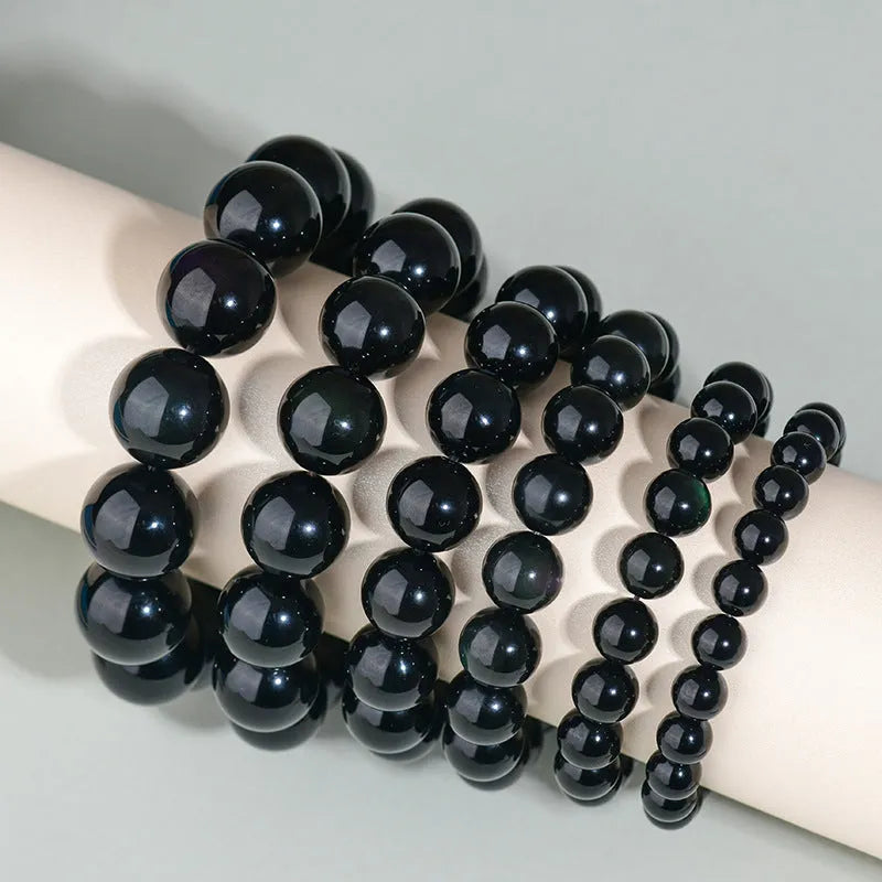 Hand-woven round obsidian crystal bracelet in ethnic style on a wrist, showing colour and bead size options.