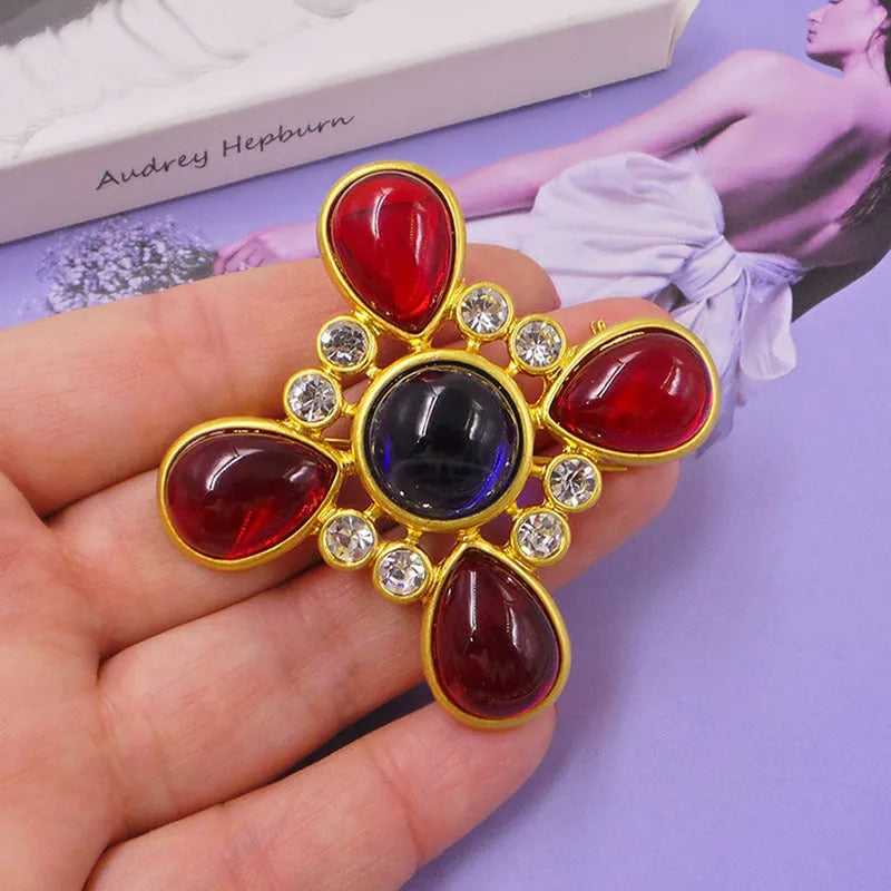 Close-up of a metallic medieval baroque cross brooch with crystal details on a dark background