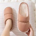 A pair of thick-soled plush slippers with artificial leather uppers and non-slip rubber soles in a choice of five colours.