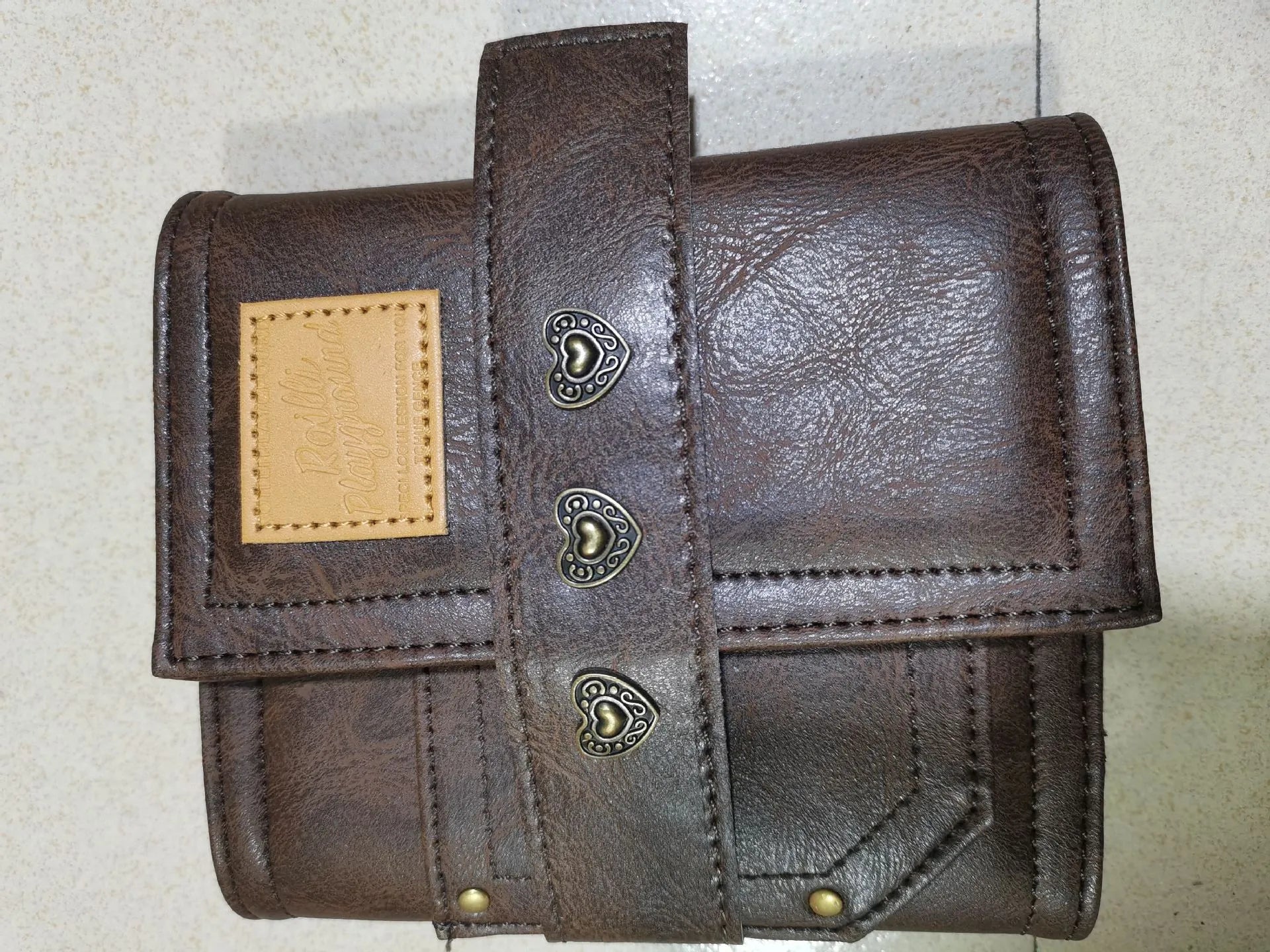 Brown retro leather-style A7 notebook with a buckle closure, shown open to reveal loose-leaf binder binding.