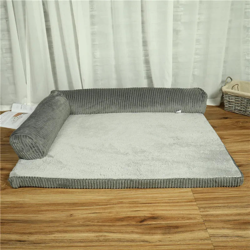 Corduroy pet sofa dog bed with bolster, shown in a grey colour on a wooden floor.