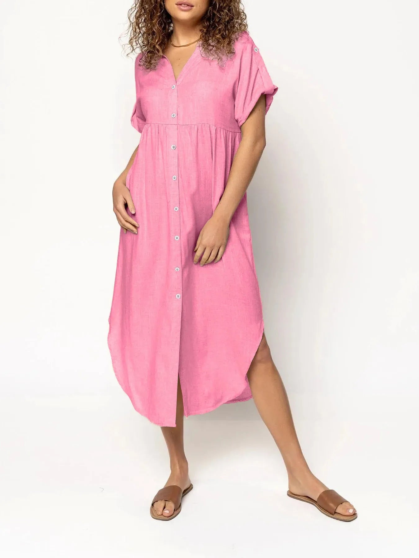 A woman wearing a loose-fitting, mid-length apricot-coloured casual dress with a button-down front.