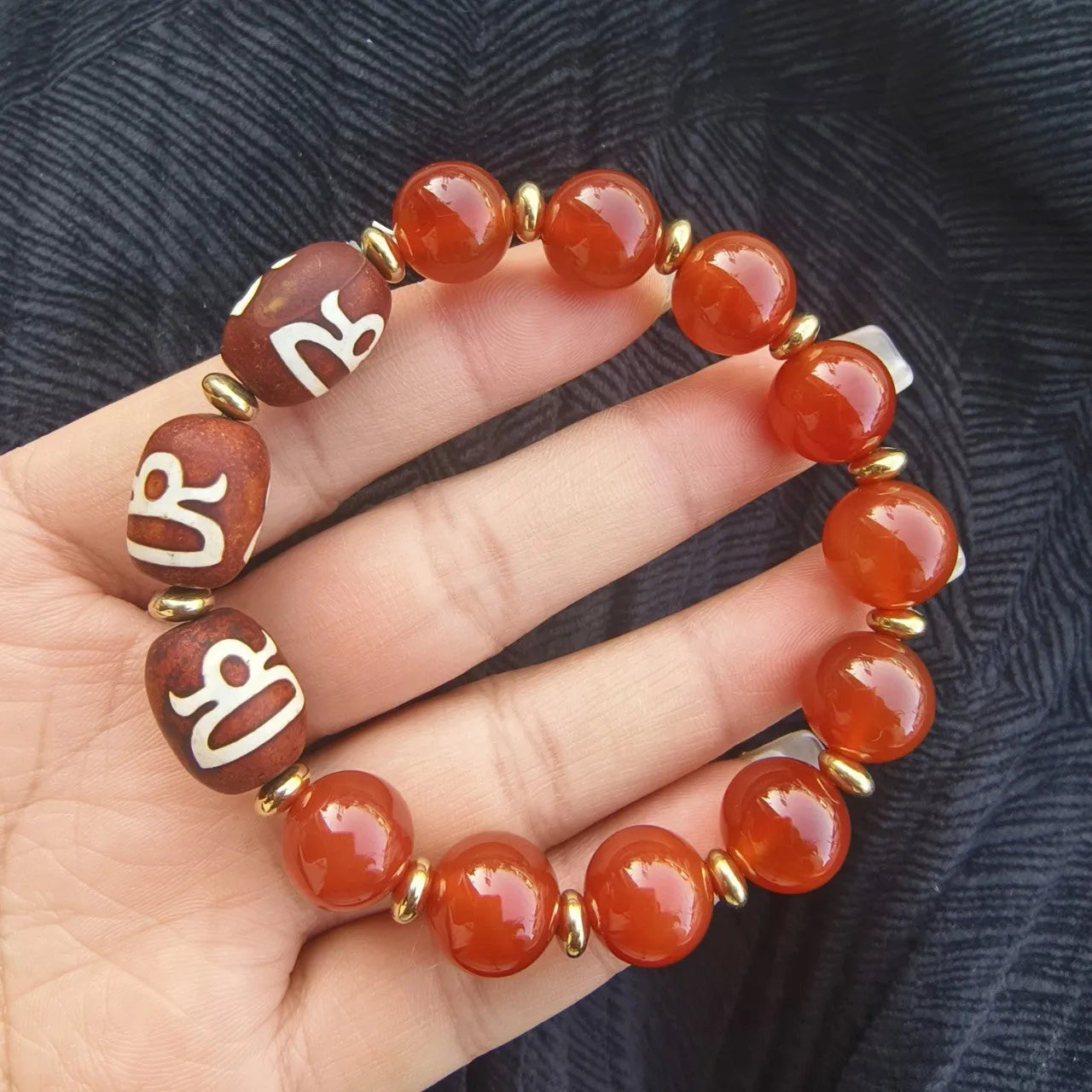 Distressed agate Tibetan bead bracelet with three-eye motifs and polished finish.