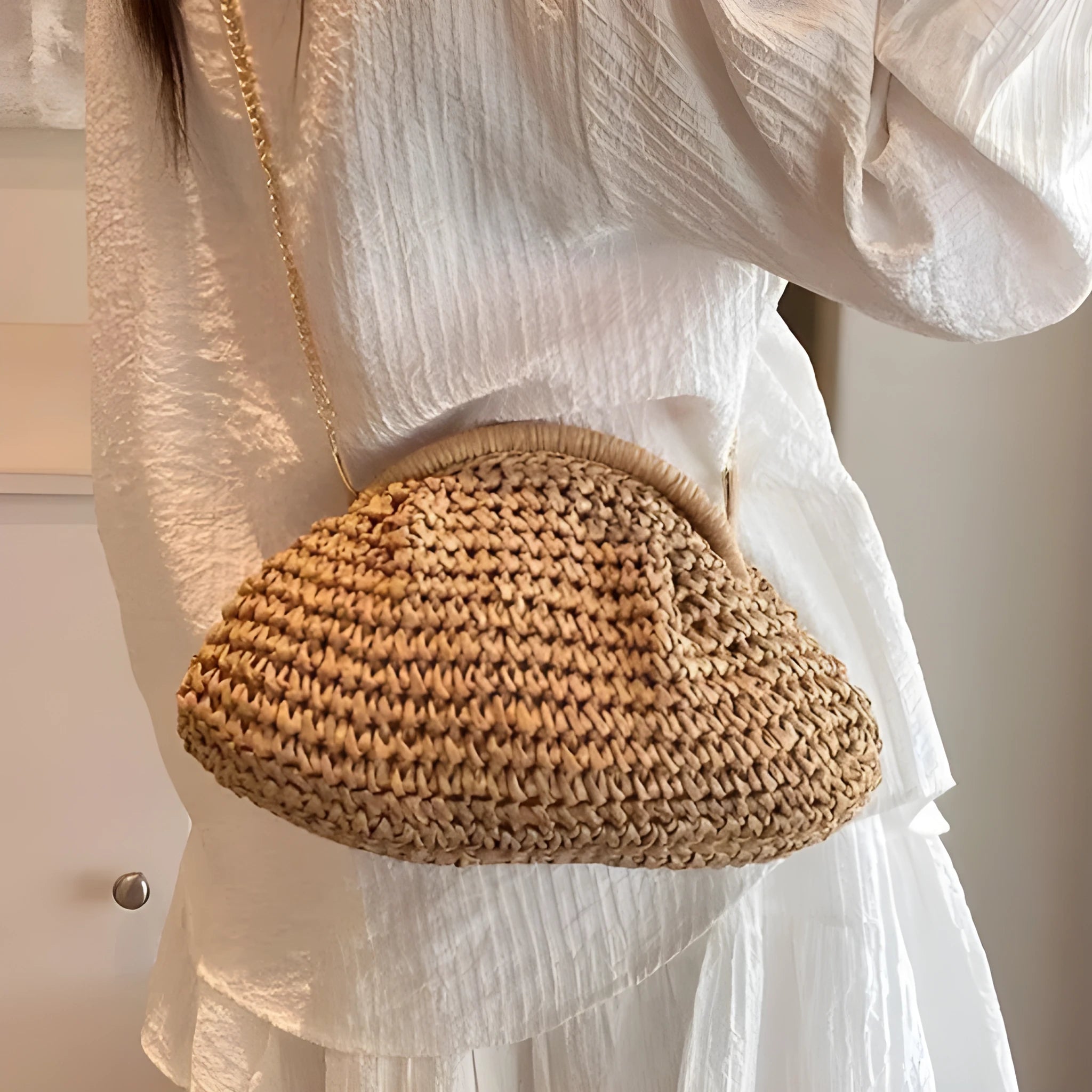 Women's khaki straw shoulder bag with chain detail and shell shape on a neutral background