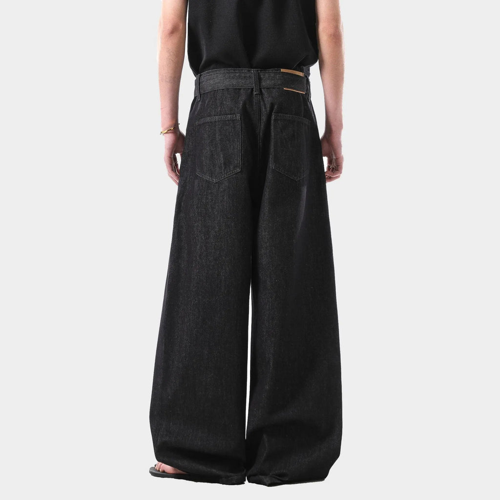 Black high-waist straight-leg jeans with gold details on a denim background.
