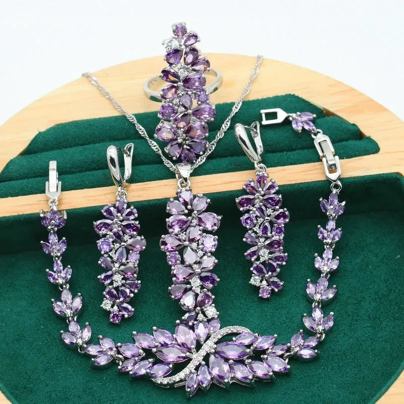 Retro style jewellery set showing necklace with floral pendant, bracelet, earrings, and ring in olive and purple colours.