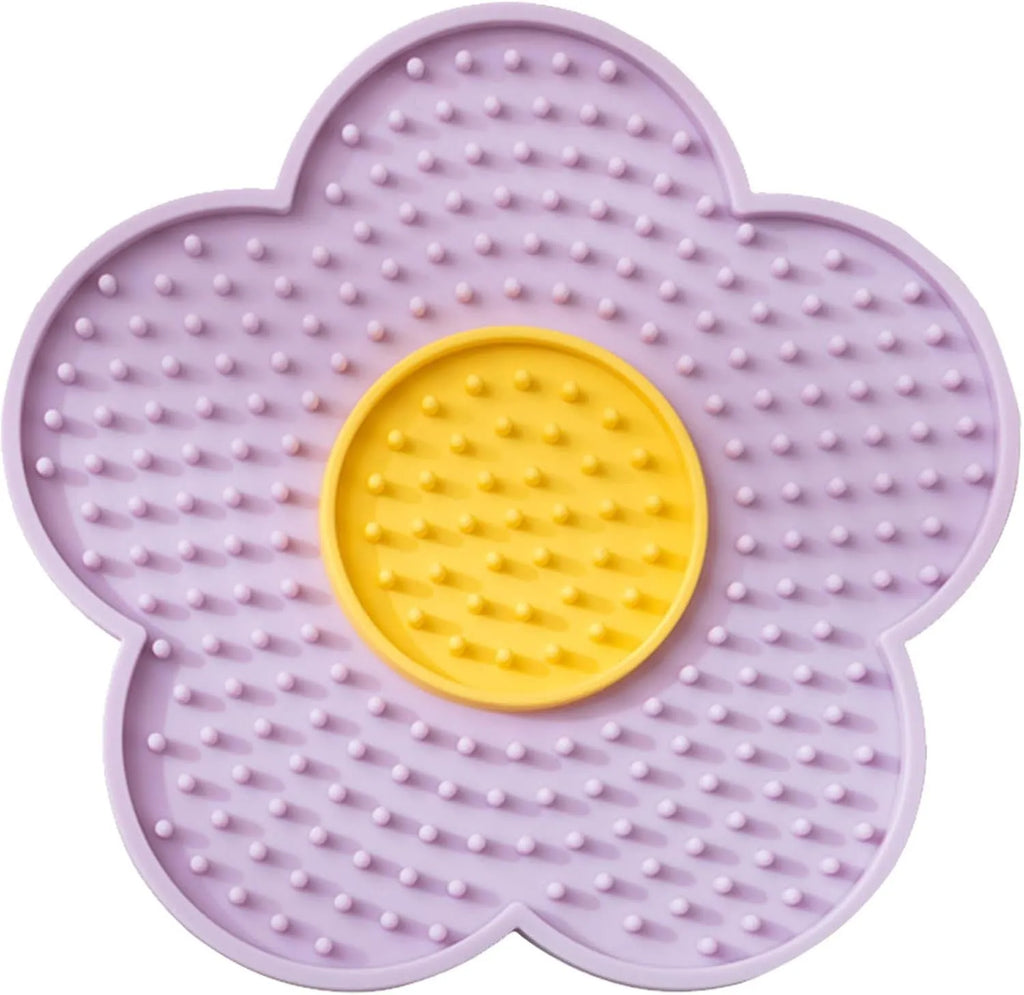 Flower-shaped blue silicone pet licking mat with suction cups on a smooth surface.
