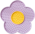 Flower-shaped blue silicone pet licking mat with suction cups on a smooth surface.