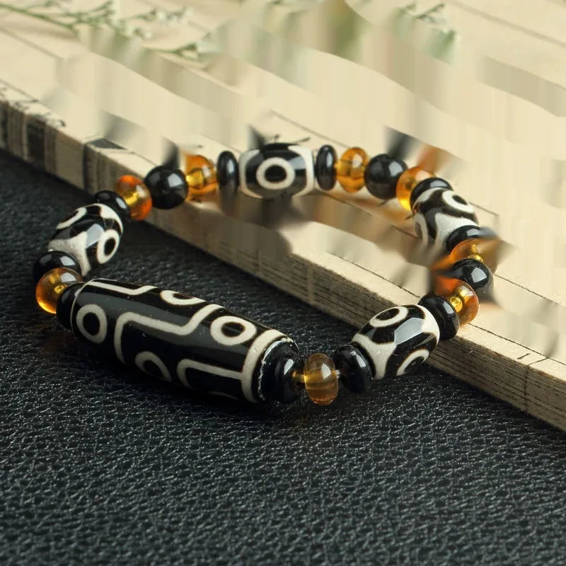 Distressed agate Tibetan bead bracelet with three-eye motifs and polished finish.