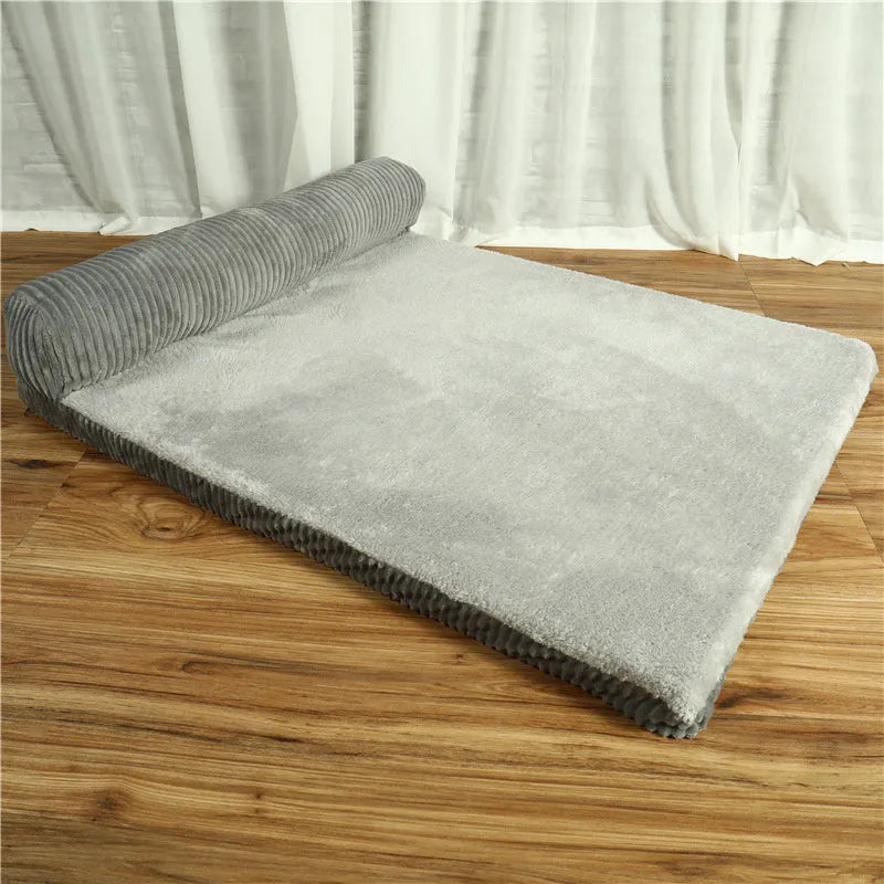 Corduroy pet sofa dog bed with bolster, shown in a grey colour on a wooden floor.