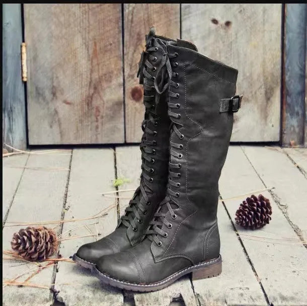 A pair of black chunky heel high leg boots with a round toe on a solid background.