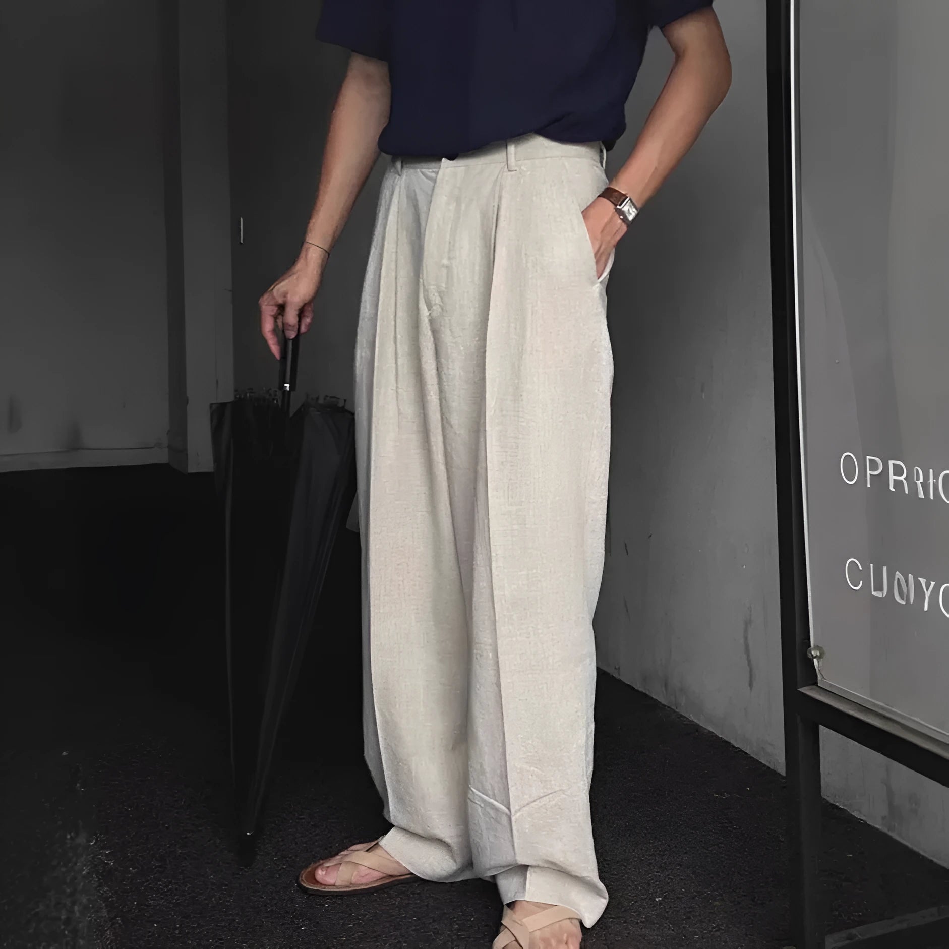 Man wearing loose fit apricot wide-leg cotton linen trousers with a zip fly and straight leg opening.