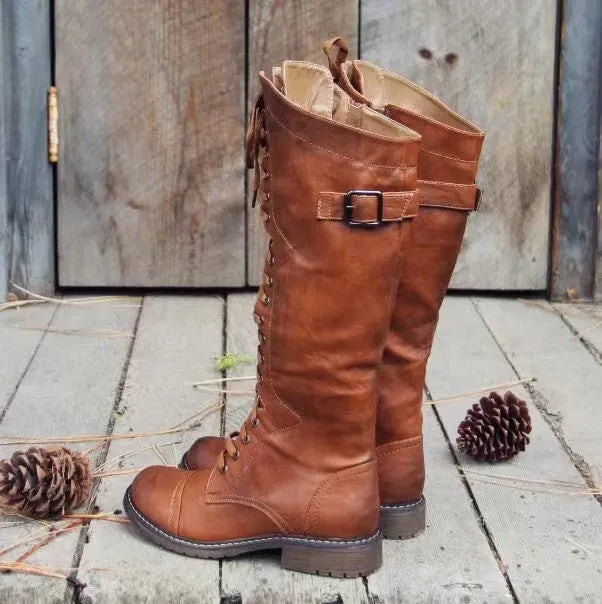 A pair of black chunky heel high leg boots with a round toe on a solid background.