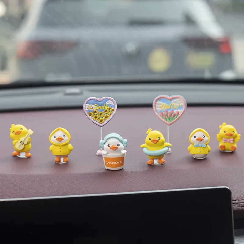 Set of six small yellow PVC duck figurines and one plastic sign for car dashboard decoration.