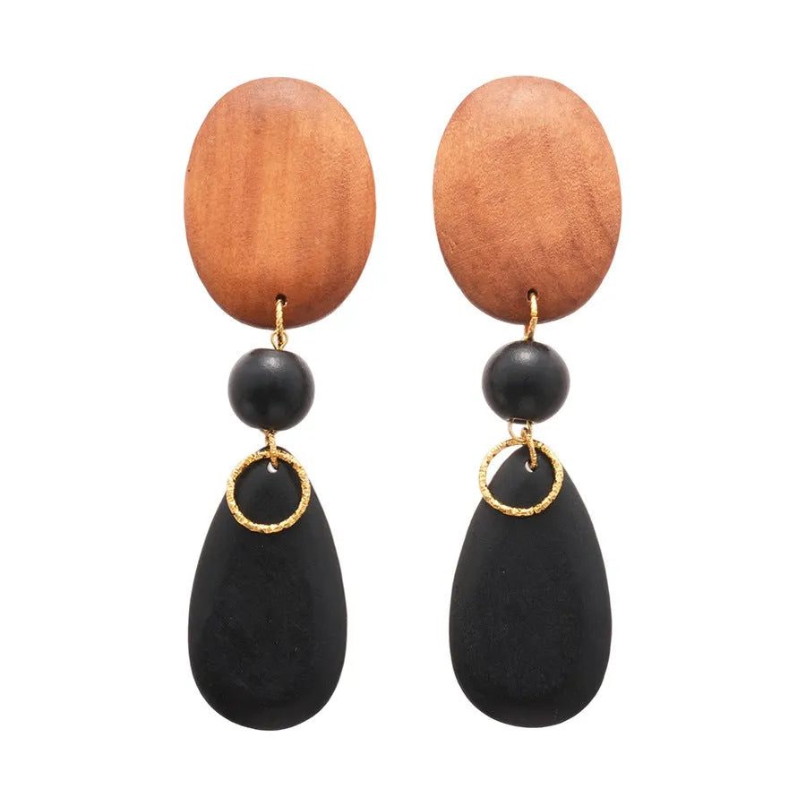 Brown and black wooden elliptical earrings with silver needle details on retro background