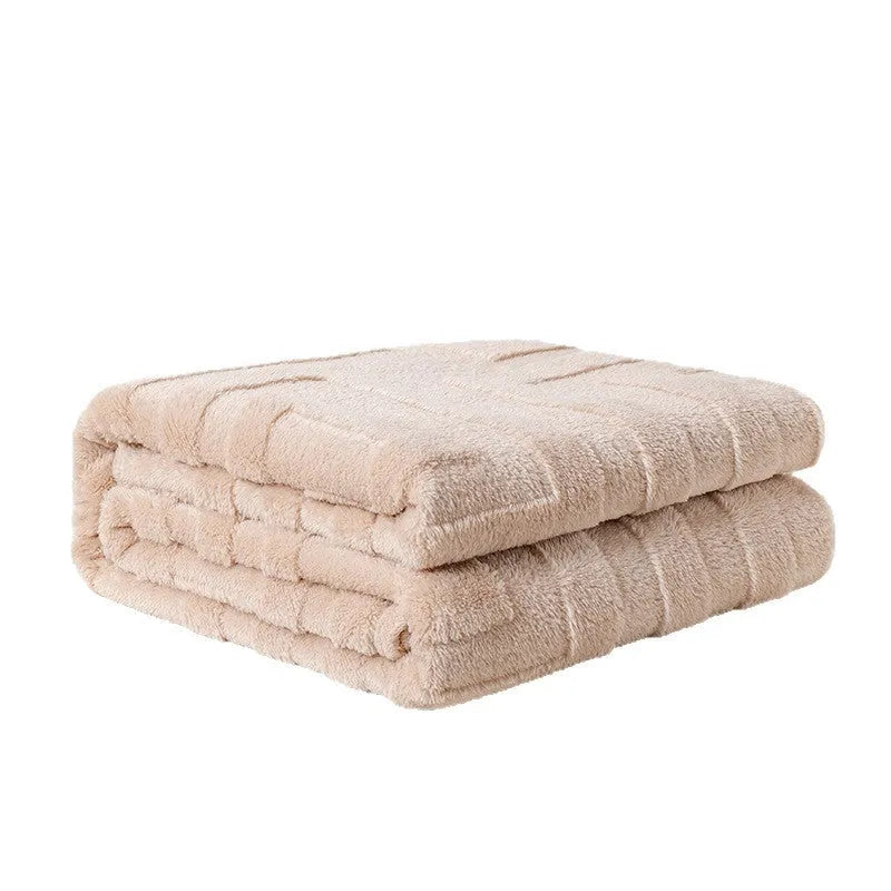 A thick, solid-colour flannel blanket draped over a modern grey sofa.