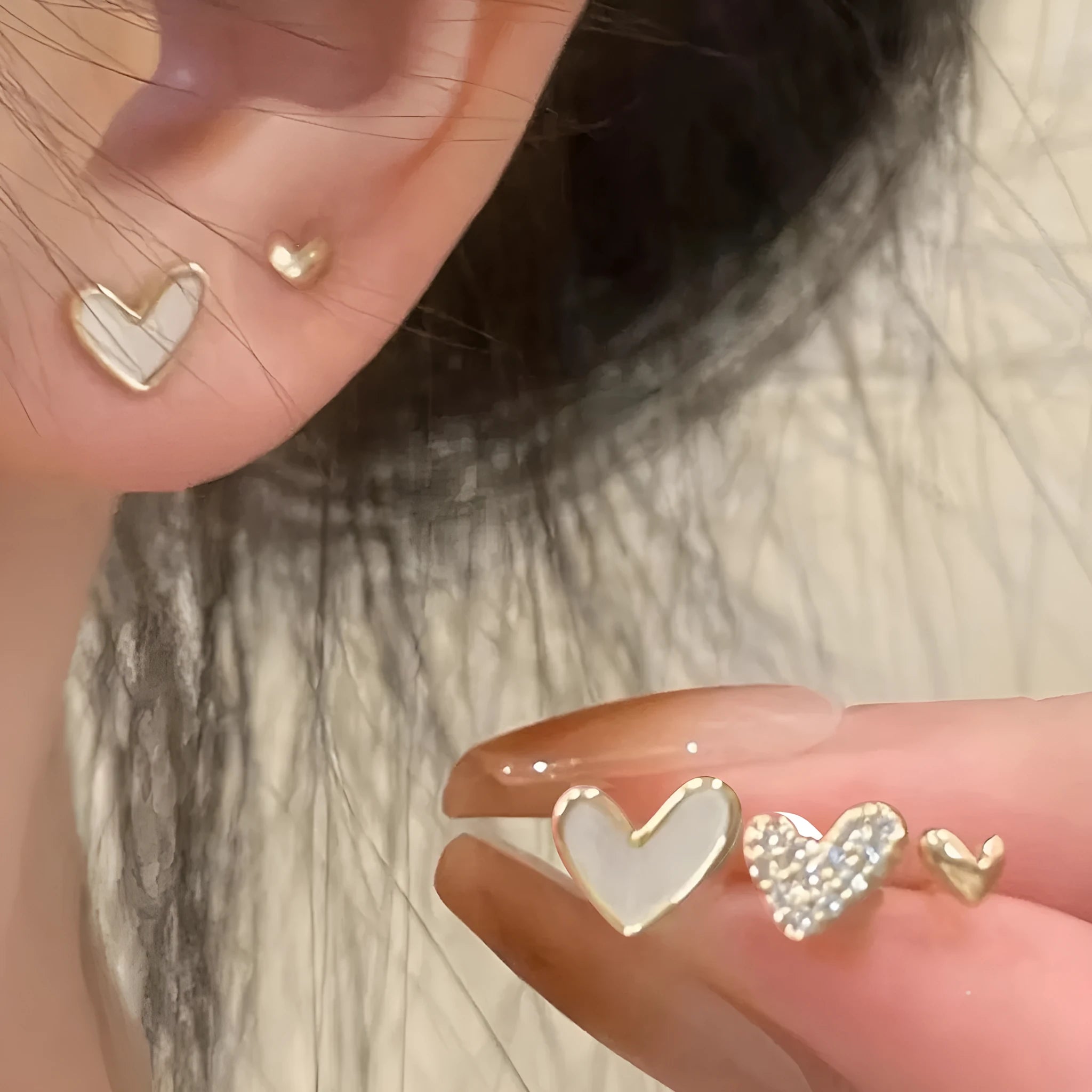 Three pairs of heart-shaped alloy earrings in gold, black, white and pink colours