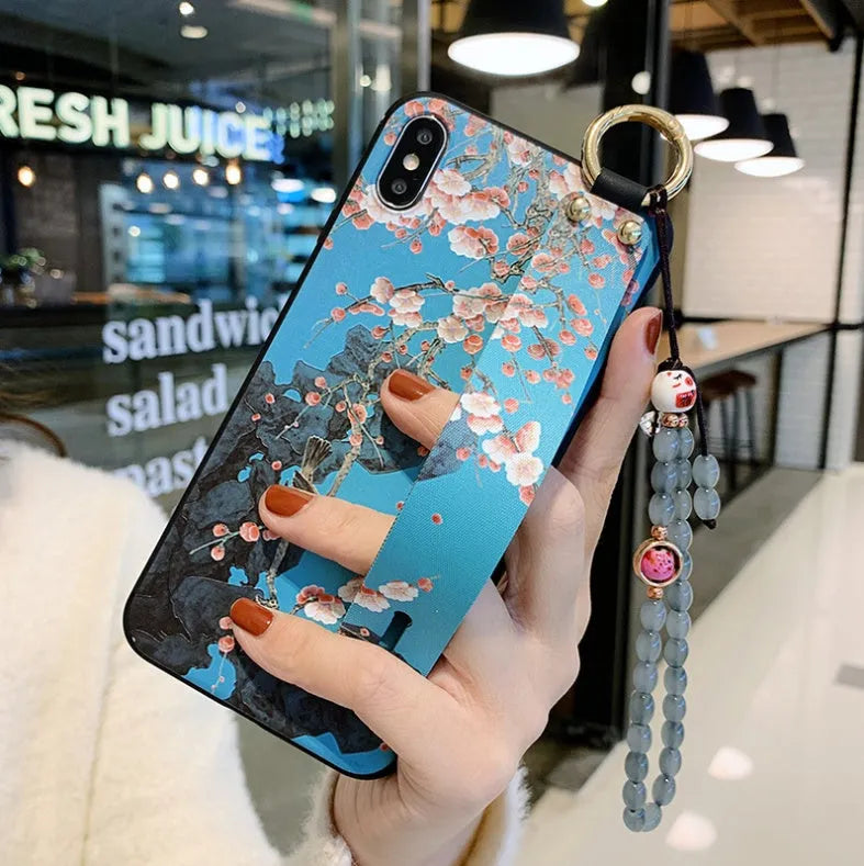 Rose flower design wrist strap case for Apple iPhone on a table.
