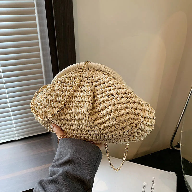 Women's khaki straw shoulder bag with chain detail and shell shape on a neutral background