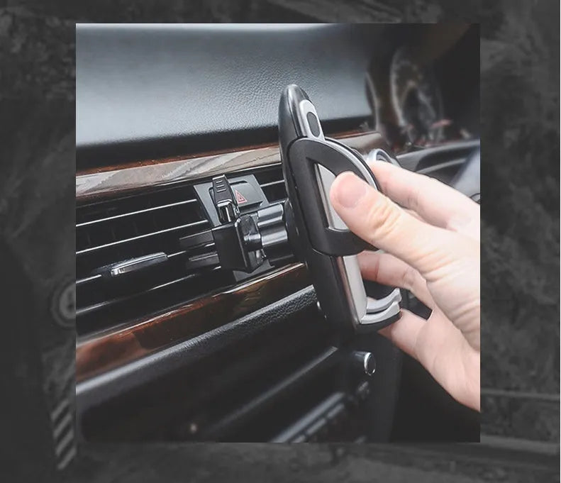 Black plastic car air vent mobile phone holder mounted on a car vent, holding a smartphone.