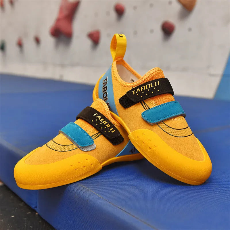 A pair of beginner rock climbing shoes with Velcro straps, shown in a black and red colour scheme.