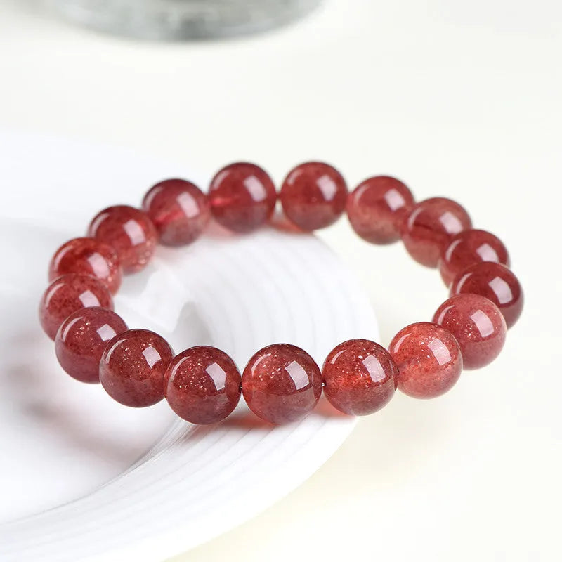 Natural cherry red strawberry quartz bracelet with polished geometric beads on a white background.