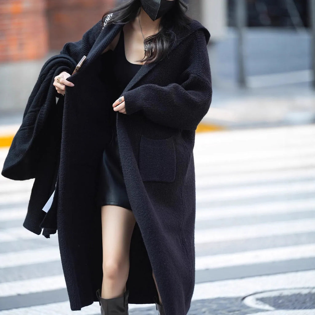 Long grey knitted hooded cardigan coat with a loose fit, shown worn open.