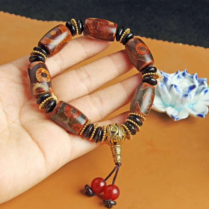 Distressed agate Tibetan bead bracelet with three-eye motifs and polished finish.