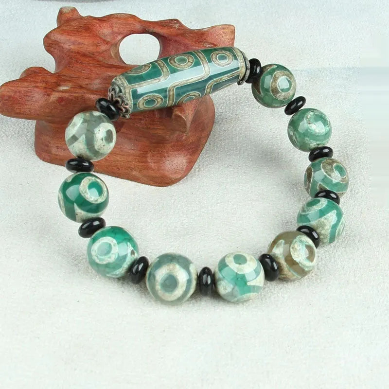 Distressed agate Tibetan bead bracelet with three-eye motifs and polished finish.