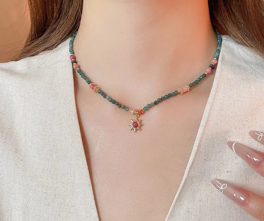 Freshwater pearl sun necklace with blue stone pendant on a gold-tone adjustable chain.