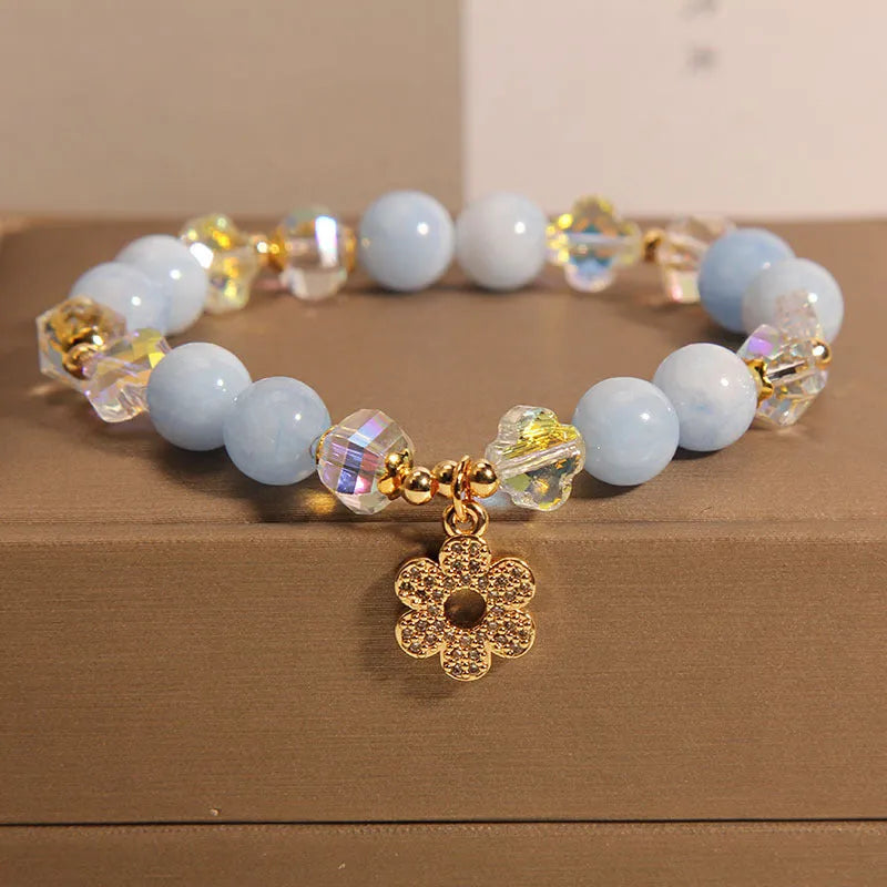 Women's aquamarine crystal bracelet with four-leaf clover charm and pearl accents on wrist