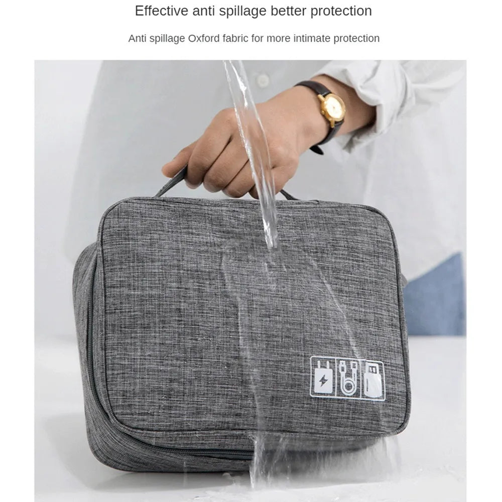 Black waterproof electronic cable organiser bag open to show mesh pockets, elastic loops, and removable padded dividers.