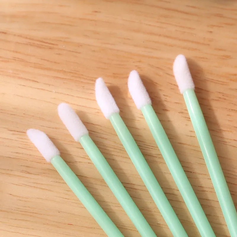 Pack of disposable flocked lip brush applicators with coloured handles on a white surface.
