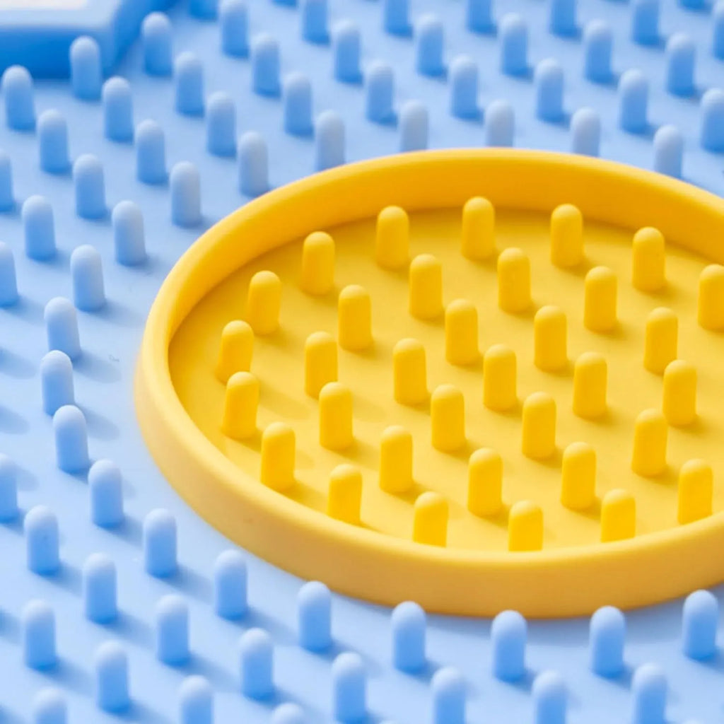 Flower-shaped blue silicone pet licking mat with suction cups on a smooth surface.