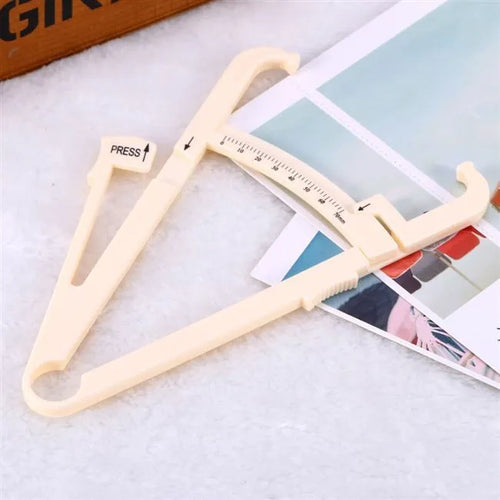 A compact, clear acrylic body fat caliper for measuring skin fold thickness, showing measurement scale.