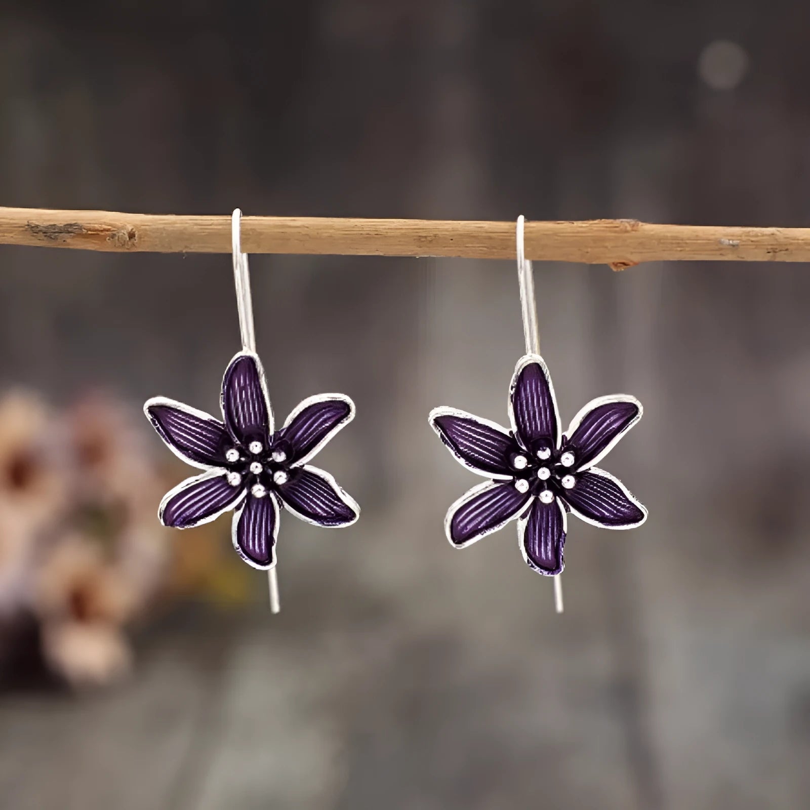 A pair of simple purple flower-shaped alloy earrings for women on a white background.