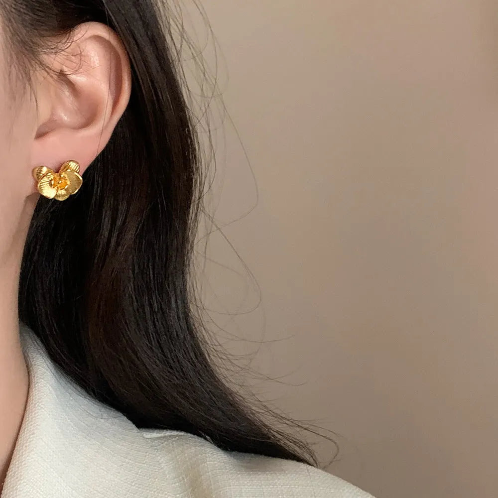 A pair of gold and silver retro-style flower earrings with petal details on a white background.