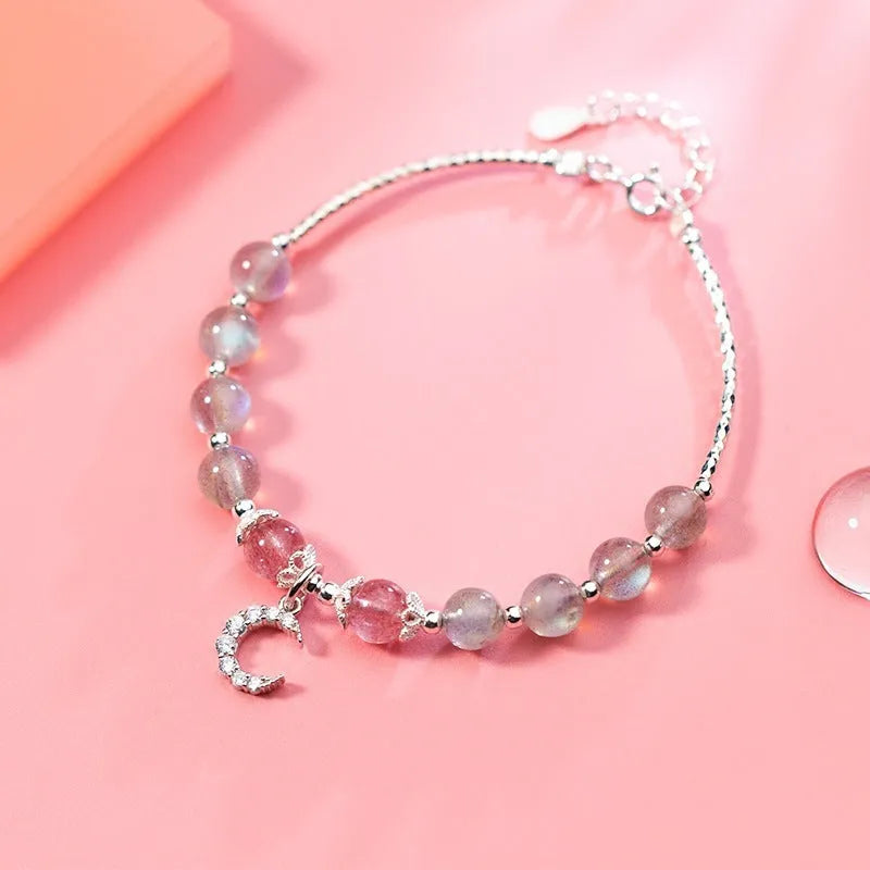 Handmade adjustable moonstone bracelet with silver crescent moon charm and crystal bead on a wrist.
