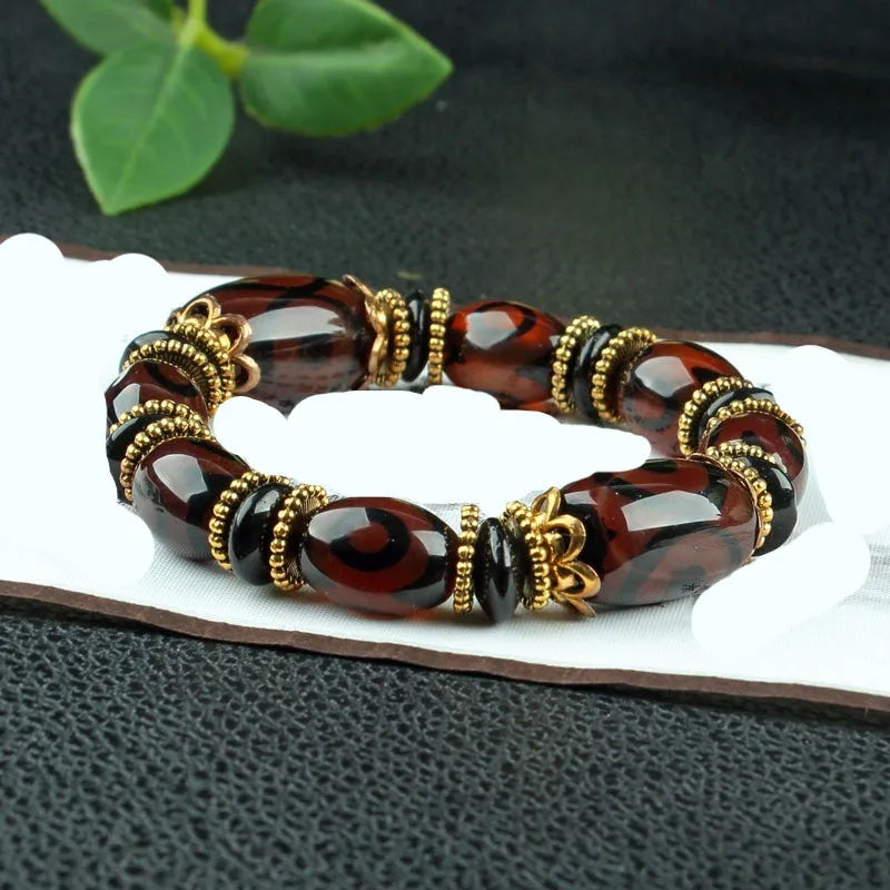 Distressed agate Tibetan bead bracelet with three-eye motifs and polished finish.