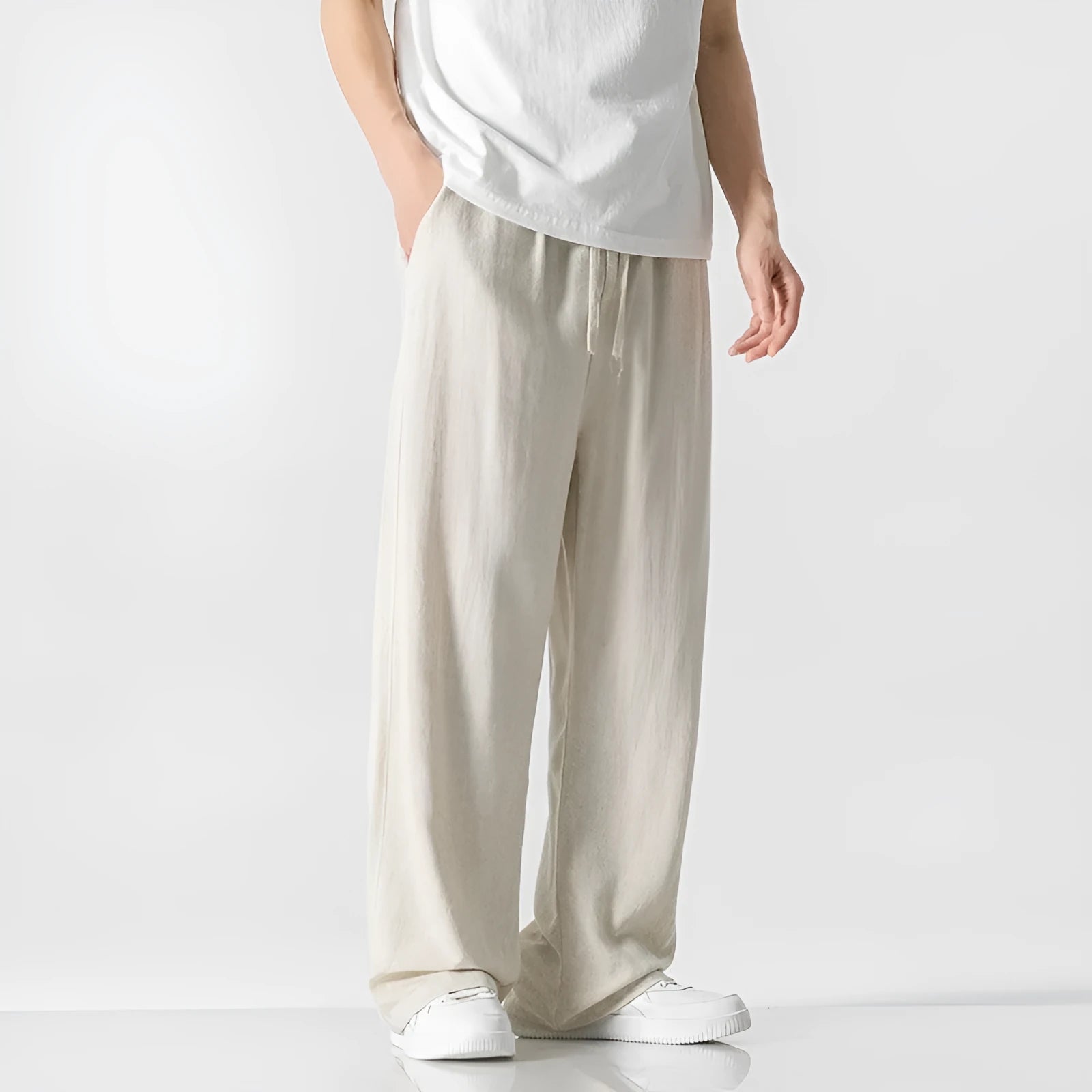 Men's beige loose-fit straight-leg linen trousers with drawstring waist, shown on a model.