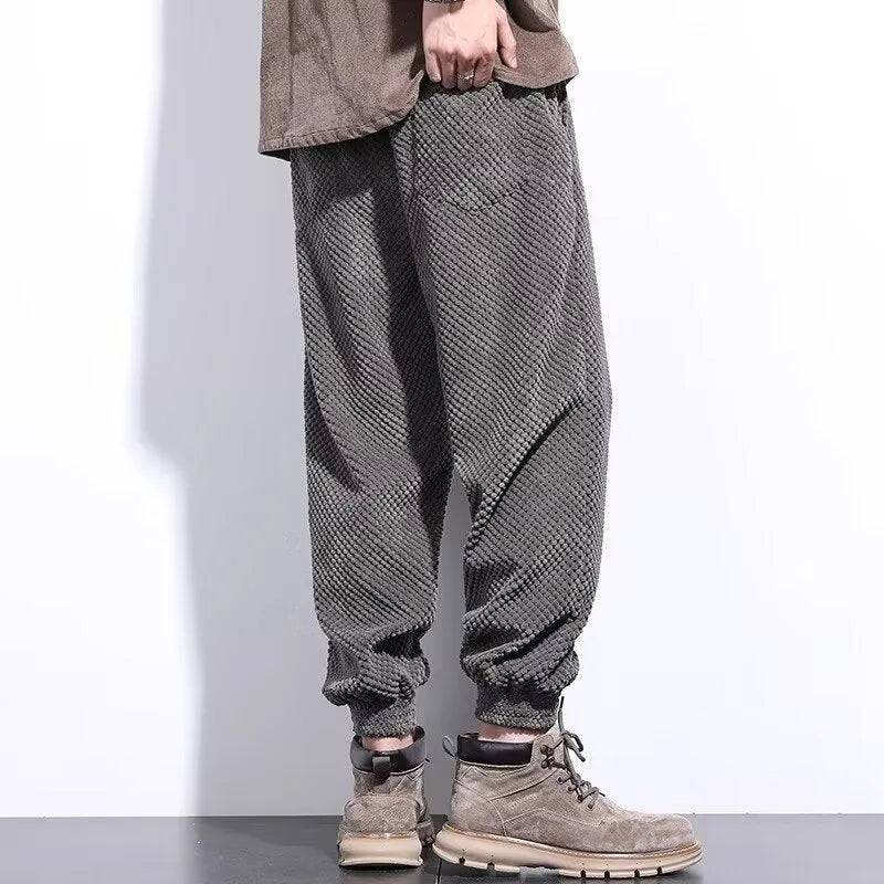 Men's grey ankle-tied straight-leg sweatpants laid flat, showing non-ironing casual design.