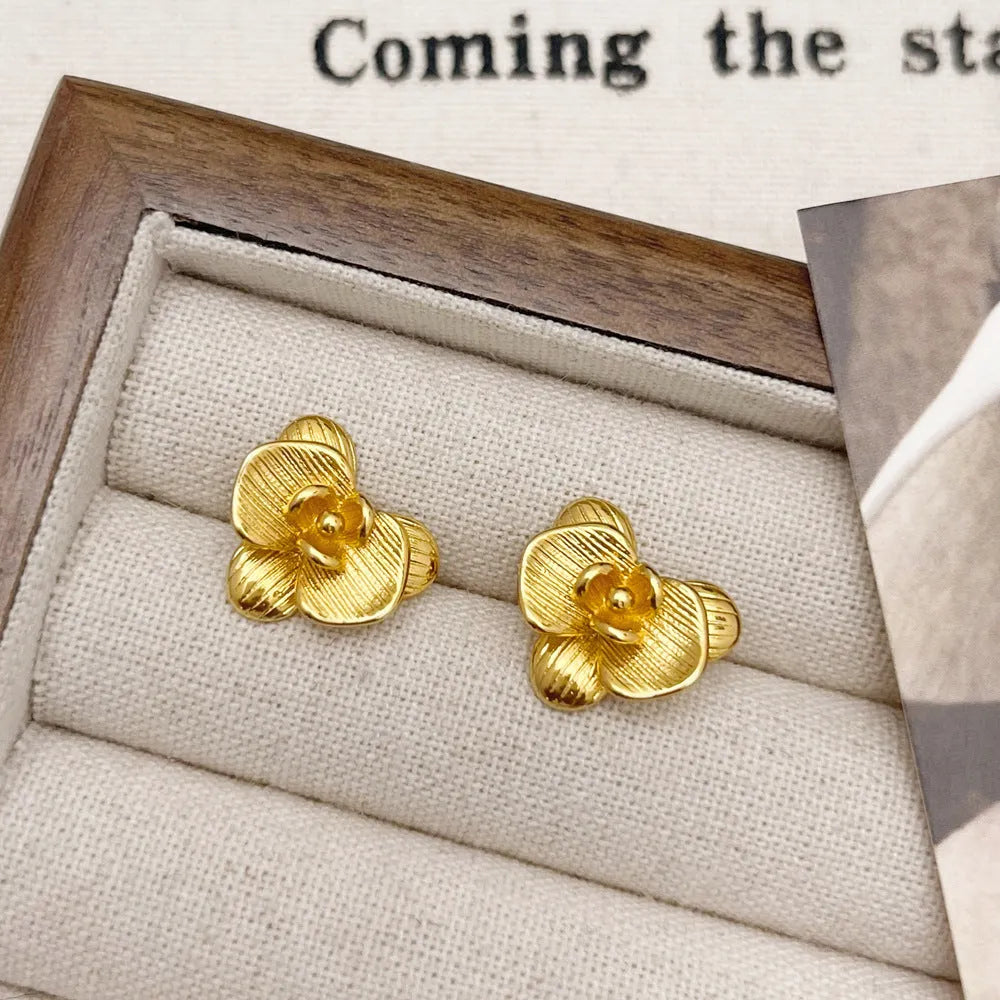 A pair of gold and silver retro-style flower earrings with petal details on a white background.