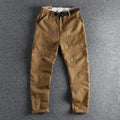 Man wearing khaki cotton work trousers with a flat front and mid-rise waist.