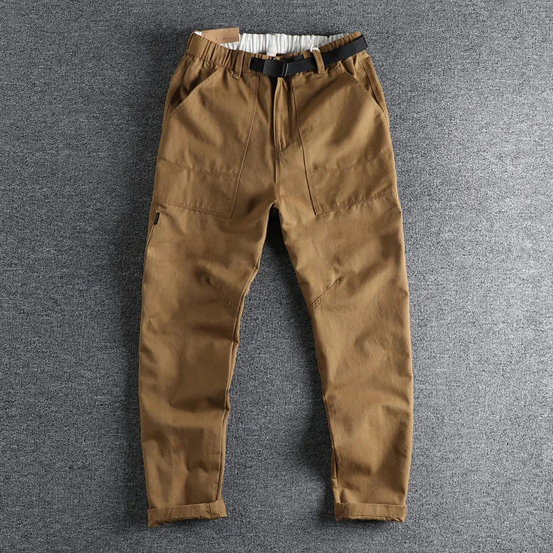 Man wearing khaki cotton work trousers with a flat front and mid-rise waist.