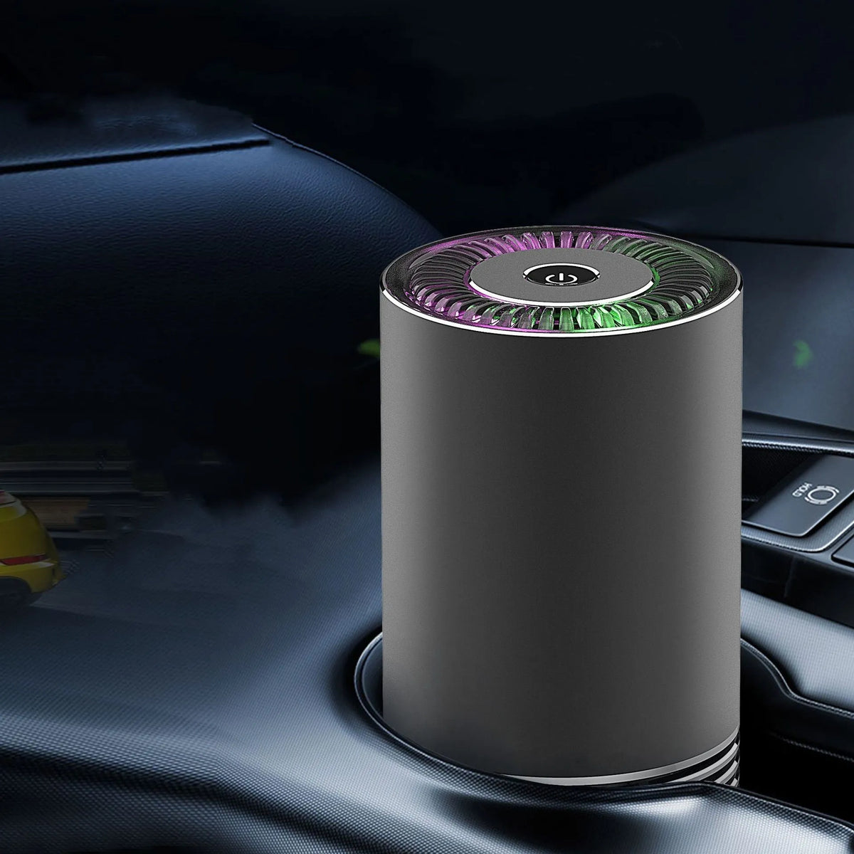 Compact cylindrical car air purifier in metallic grey with USB cable, shown next to a car vent for scale.