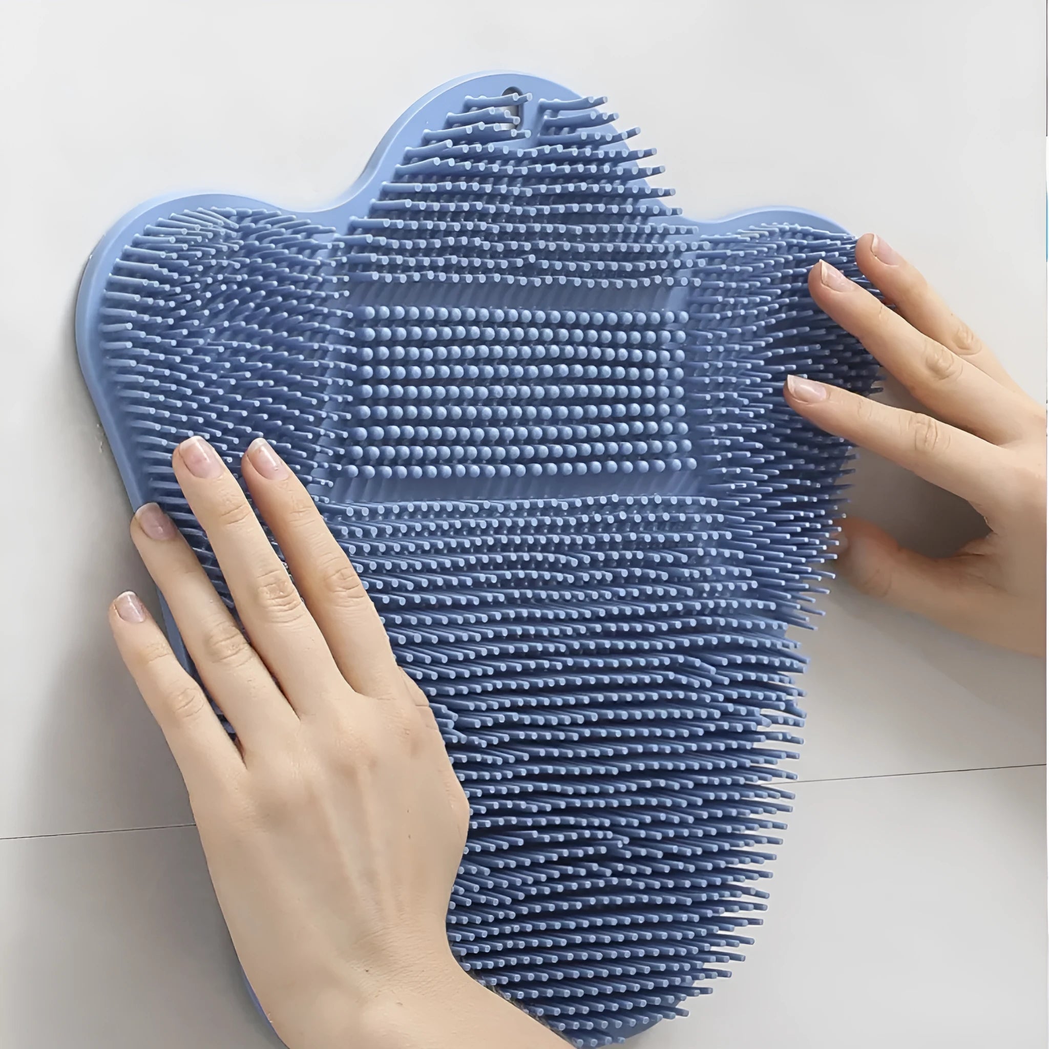 Blue silicone bath massage cushion mat for body scrubbing, shown on a bathroom surface.