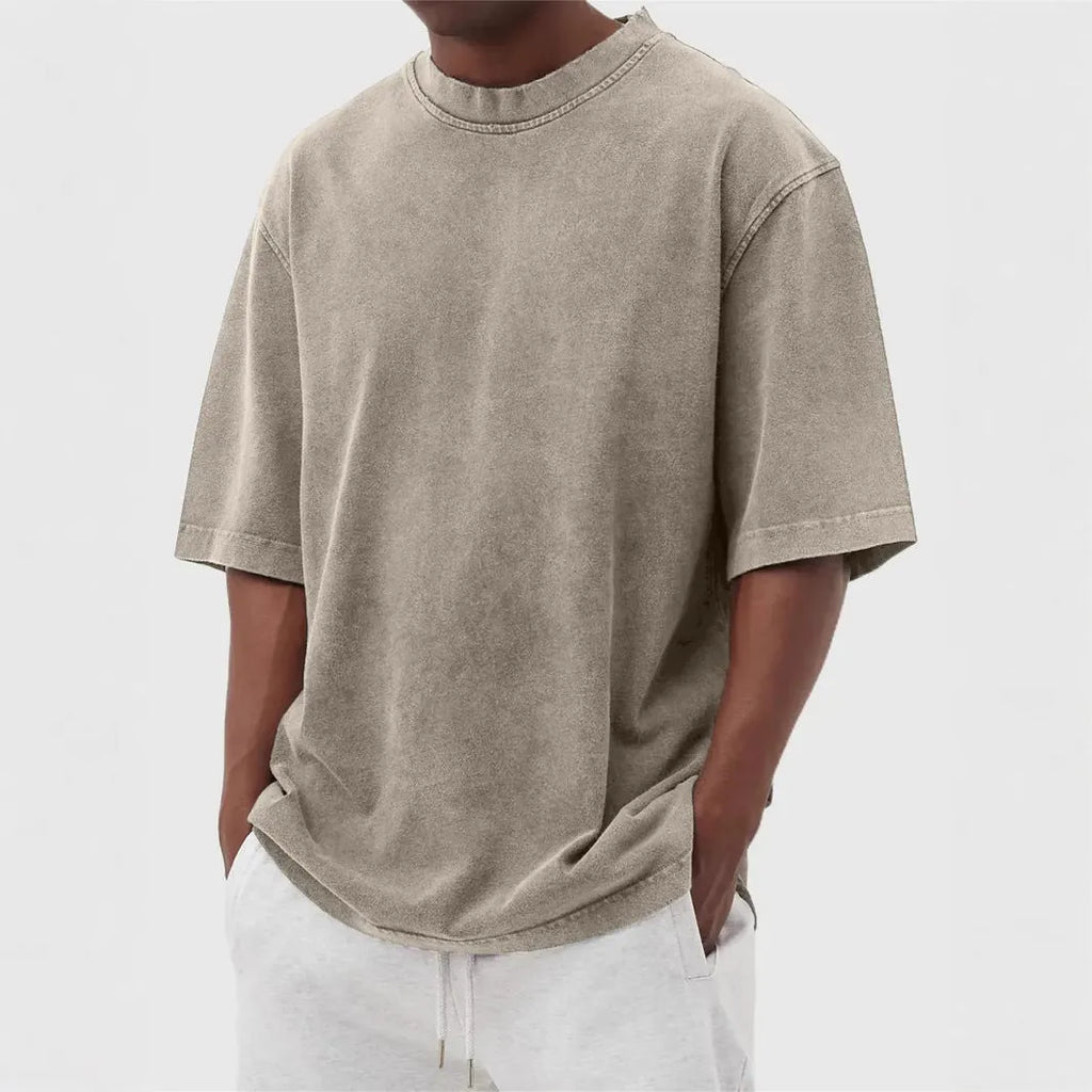 A man's loose-fit, stone-washed pullover t-shirt in a solid colour, shown on a hanger.