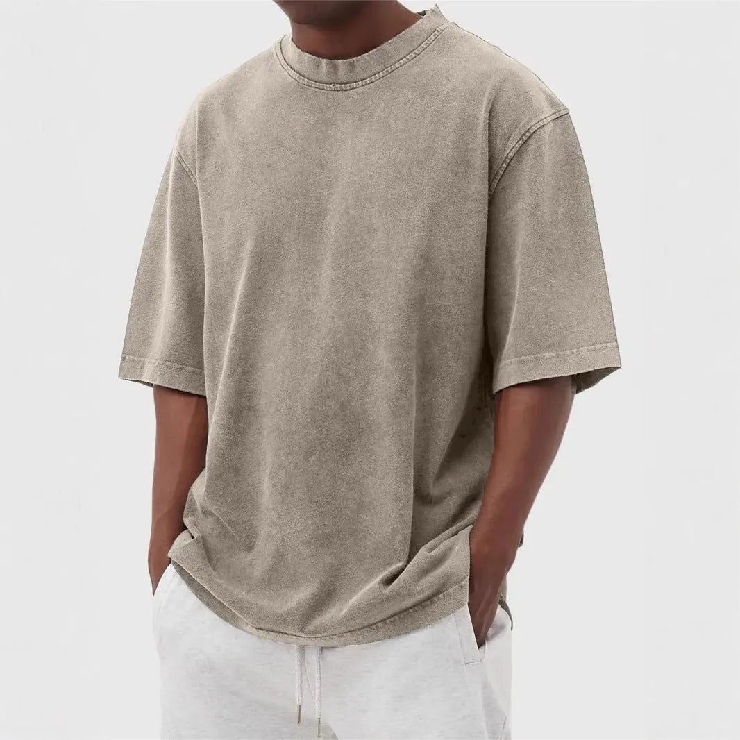 A man's loose-fit, stone-washed pullover t-shirt in a solid colour, shown on a hanger.