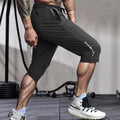 Man wearing grey cropped nylon ice silk sports pants with a straight-leg design on a beach.
