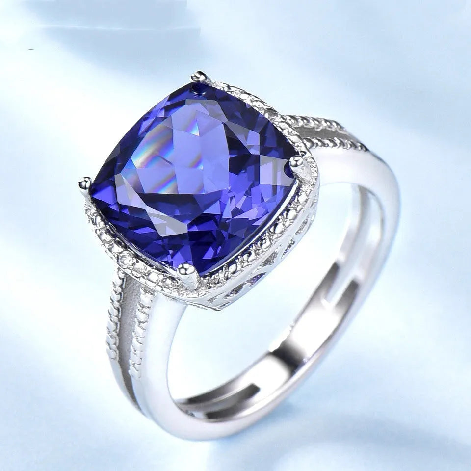 Blue tanzanite gemstone set in a sterling silver women's ring on a plain background.